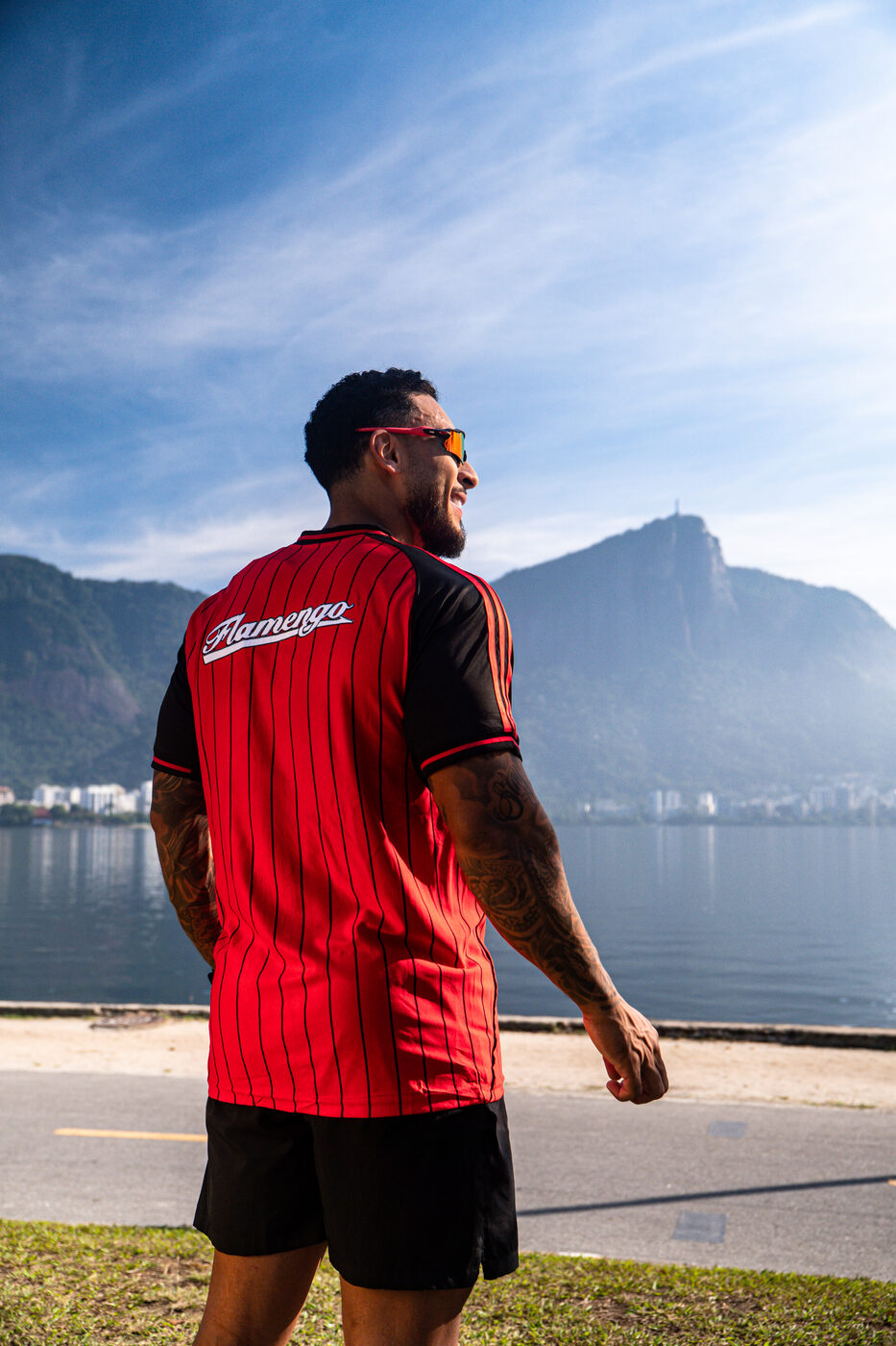 Casal vestindo camisas do Flamengo sentado em frente ao mar